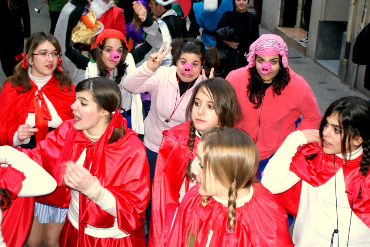 Grupo de alumnas con capas rojas y narices de cerdito en el desfile de carnaval