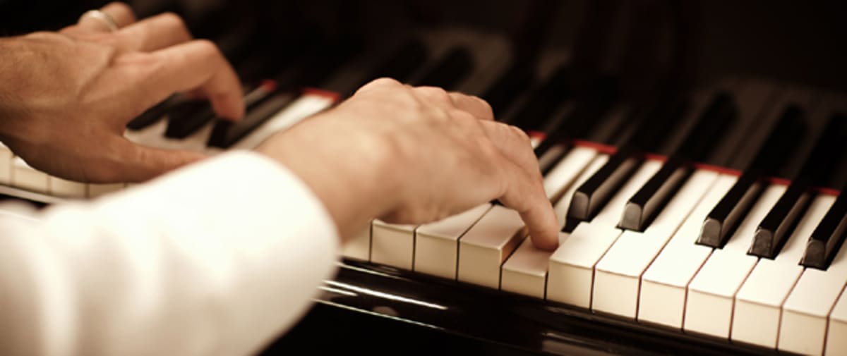 Primer plano de dos manos tocando las teclas de un piano