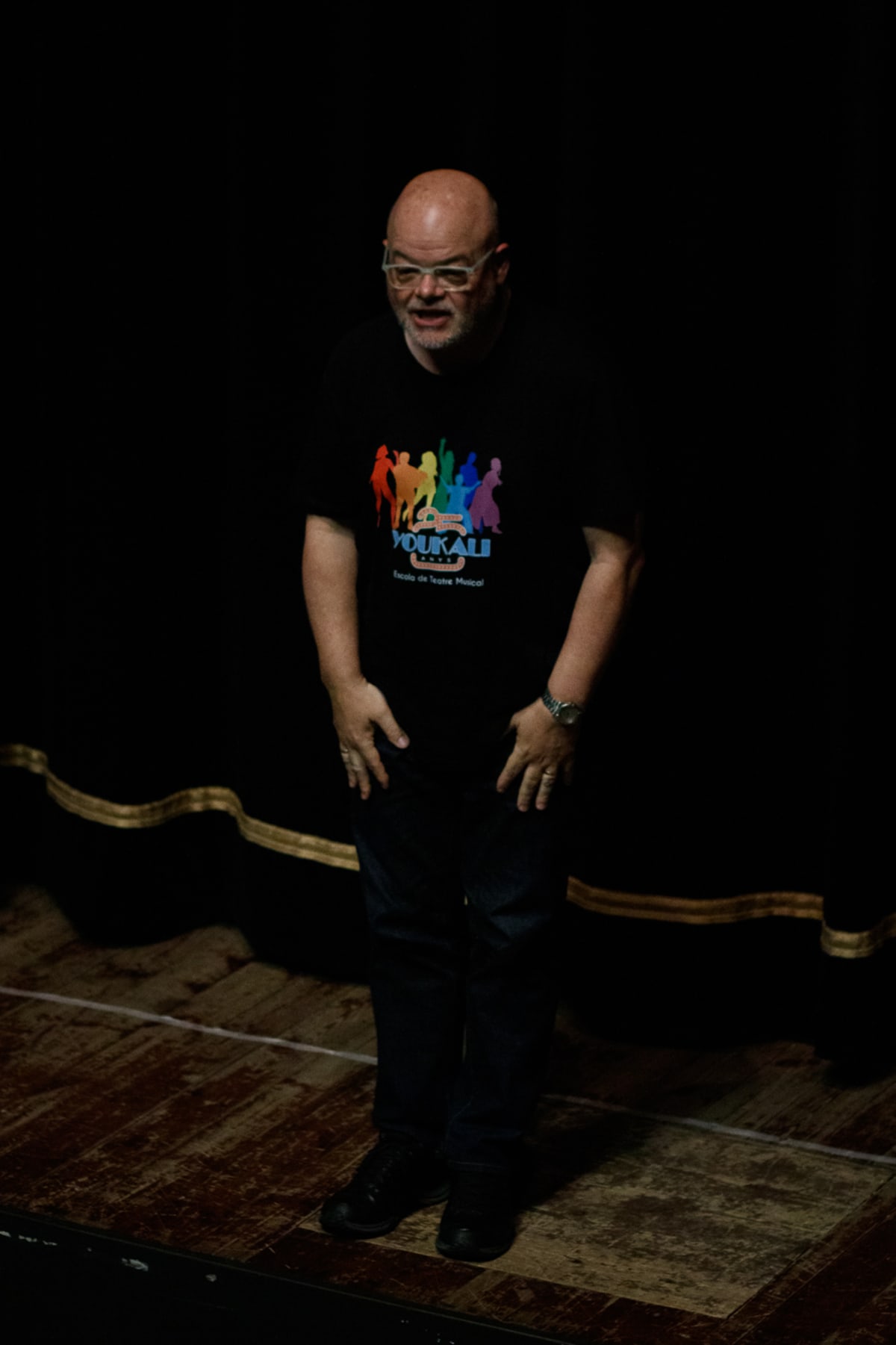 Un profesor con la camiseta de la escuela se dirige al público desde el escenario