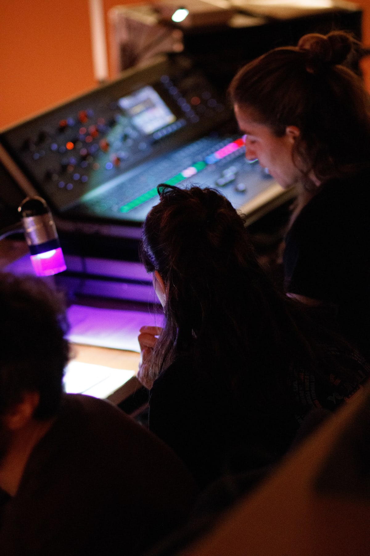 Dos personas manejan la mesa de sonido y luces desde la cabina durante la función
