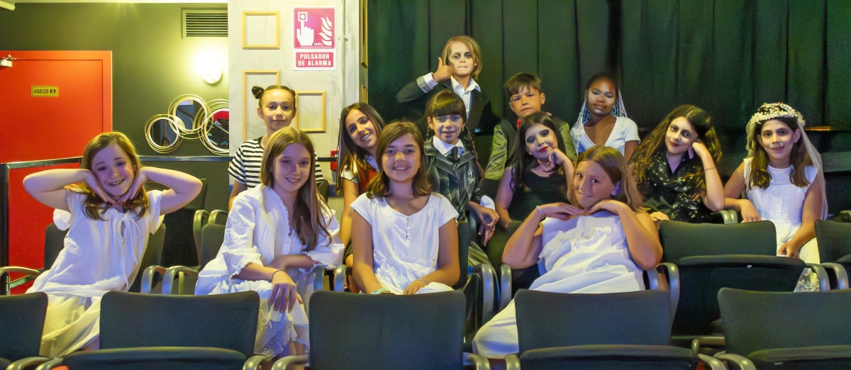 Grupo de alumnos caracterizados, sentados en las butacas antes de salir a escena