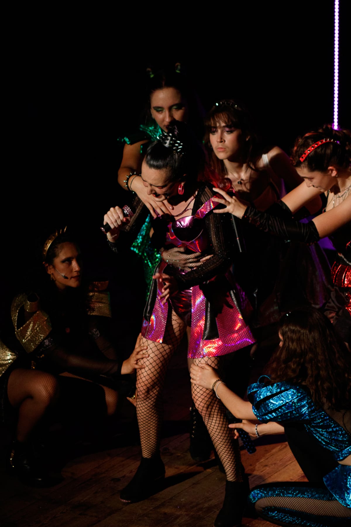 El grupo de Six rodea a la cantante central entre neones lila