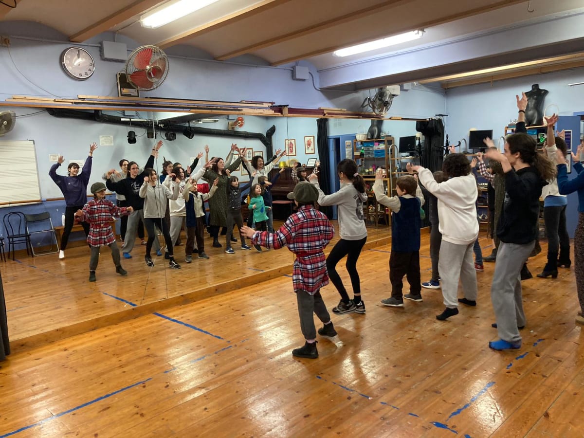 Grupo en círculo con los brazos en alto durante un ejercicio en la sala de ensayo