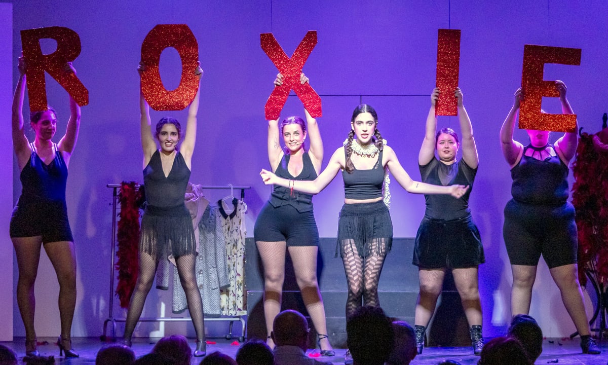 Seis intérpretes levantan las letras brillantes que forman ROXIE sobre el escenario