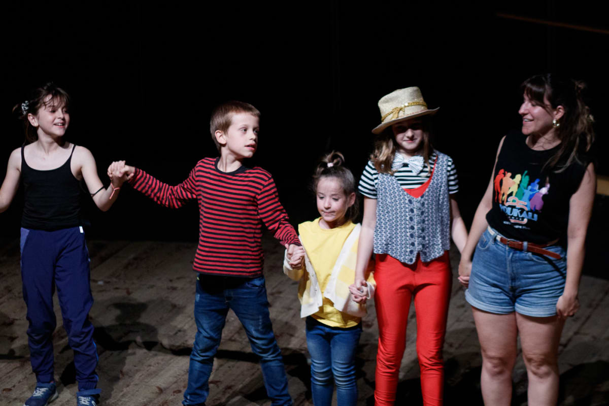 Nens i monitora agafats de la mà saluden al final de Charlie i la fàbrica de xocolata