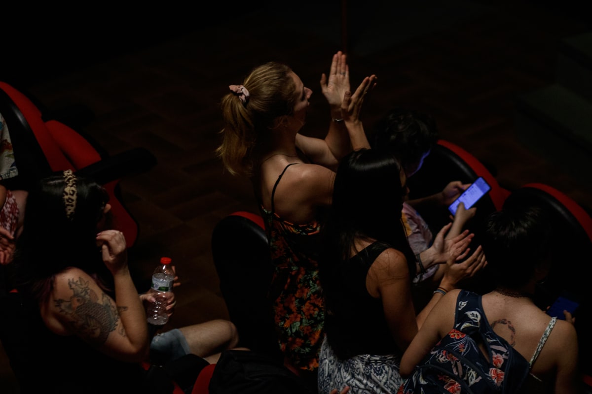 Públic assegut a la platea a les fosques, una espectadora aplaudint