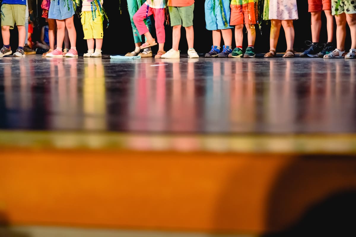 Piernas y zapatillas de colores de niños alineados en el borde del escenario