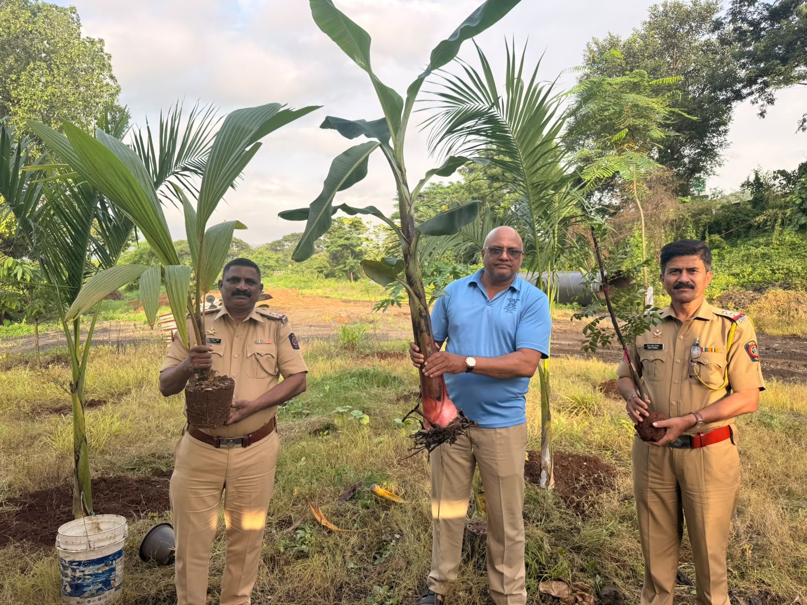 Police officers from Panvel holding coconut and banana saplings with a volunteer