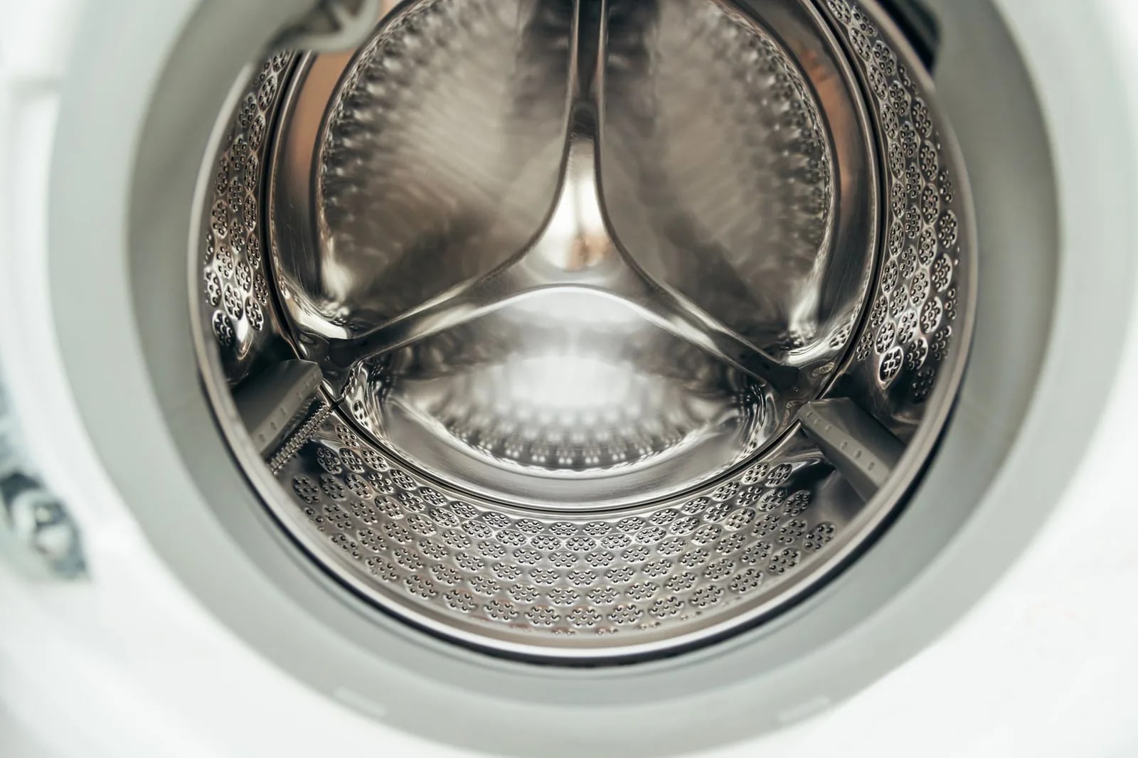 The stainless steel drum of a front-loading washing machine seen through its open door