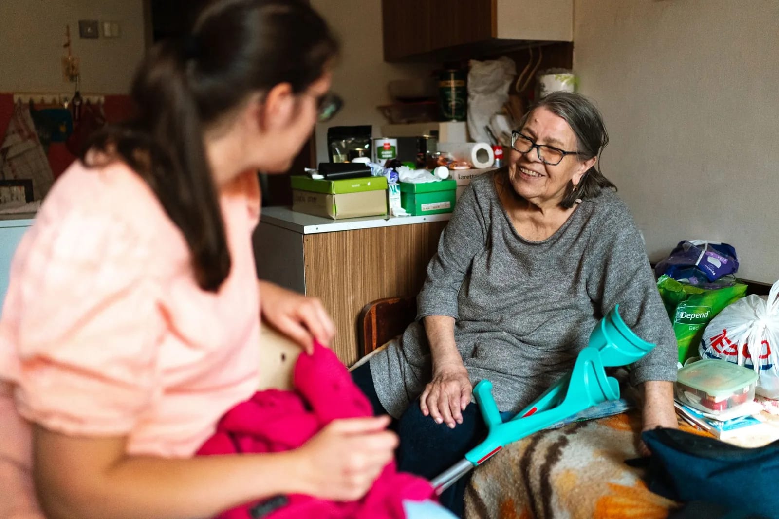 A caregiver sitting with an older adult in a bright indoor room