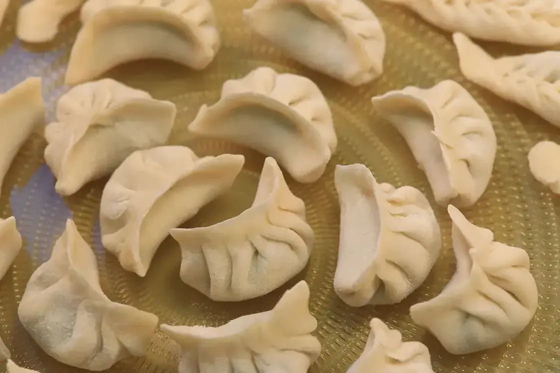 Rows of pleated dumplings arranged on a plate