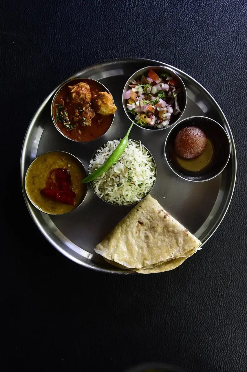 An Indian thali of small curry bowls served with rice and flatbread
