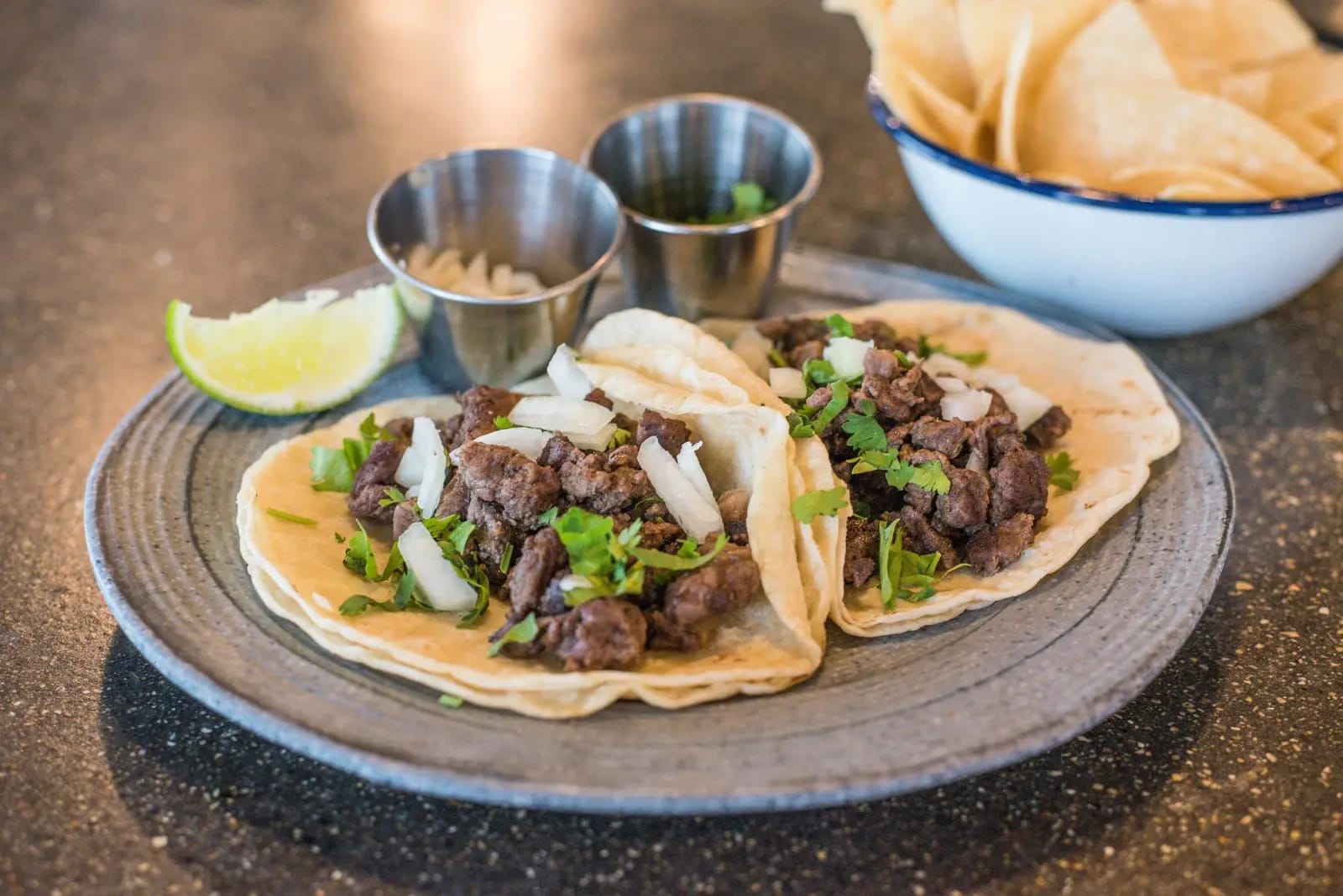 Beef tacos topped with cilantro and lime on a plate
