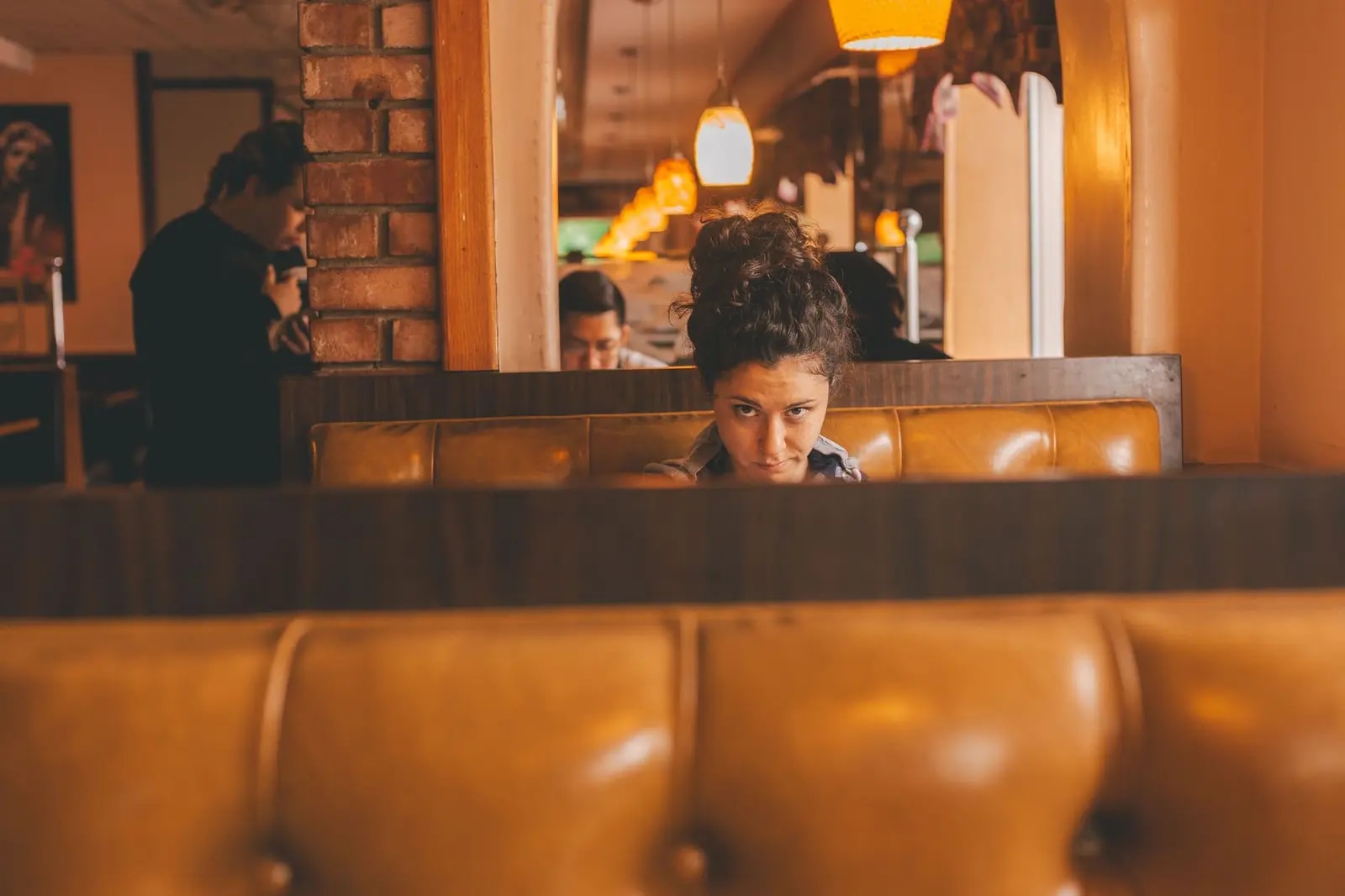 Warm and inviting restaurant interior with a woman seated in a booth