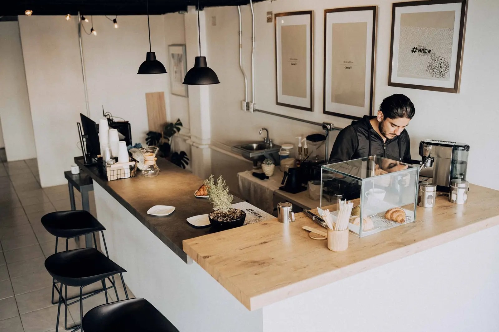 A barista works in a modern café with minimalistic décor and warm lighting