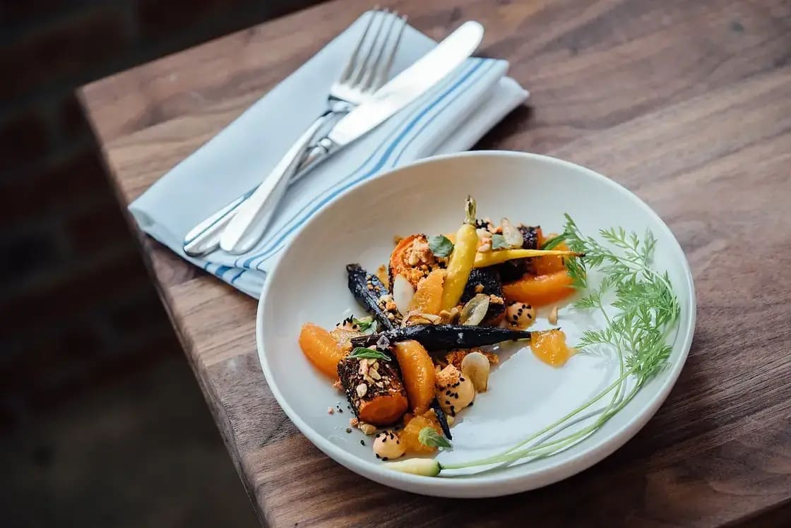 A plated dish of roasted vegetables and grains on a restaurant table