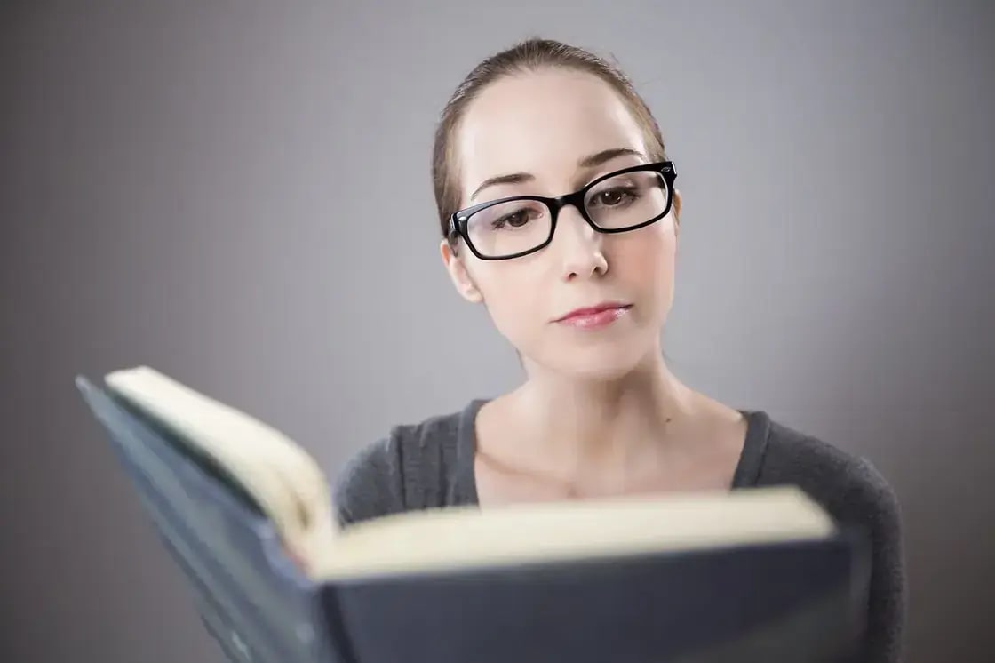A student in glasses reading an open book