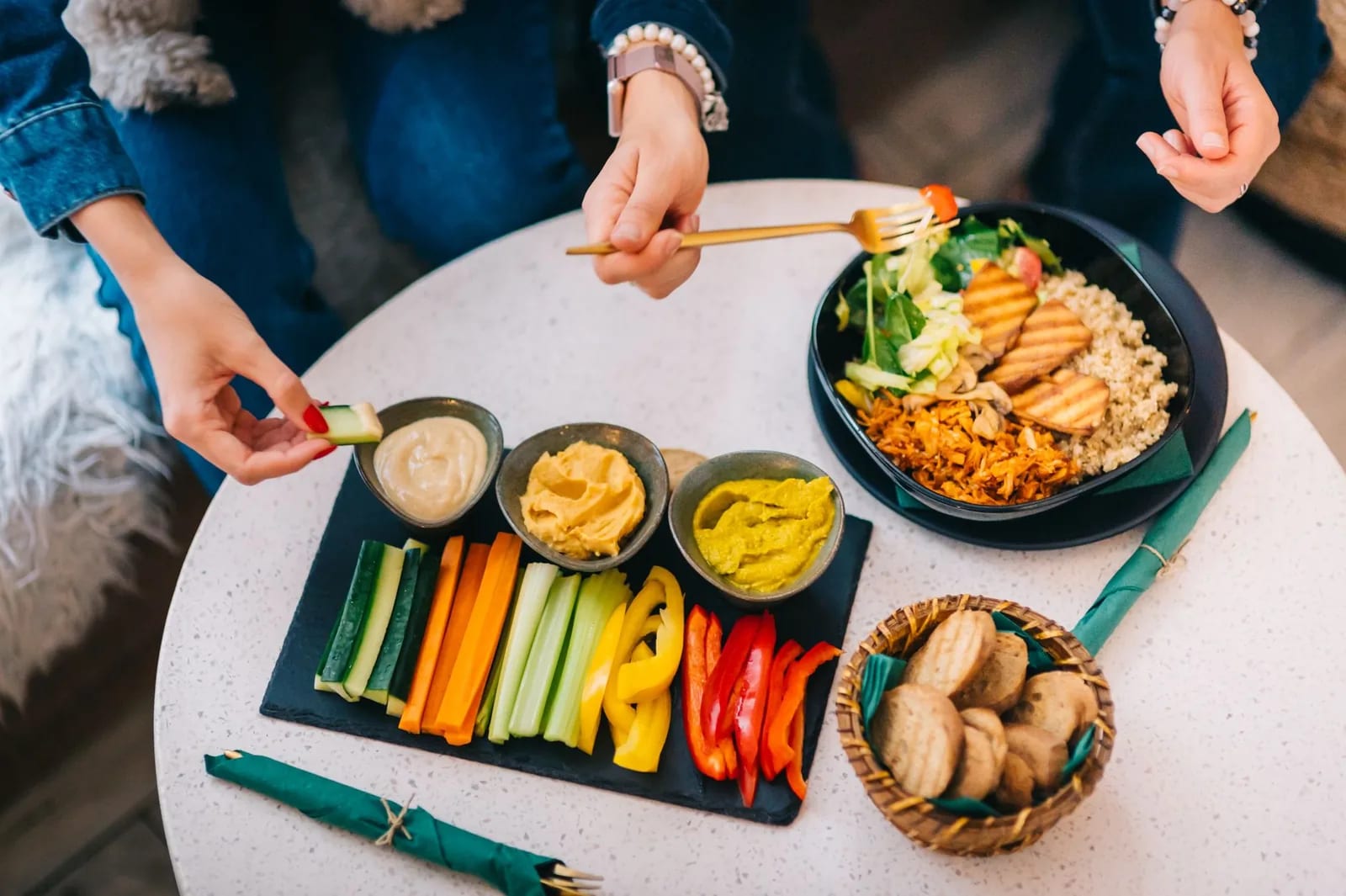 A platter of raw vegetables and dips shared across a table