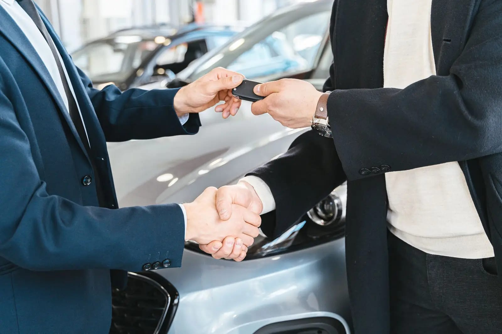 Two people shaking hands as car keys change hands