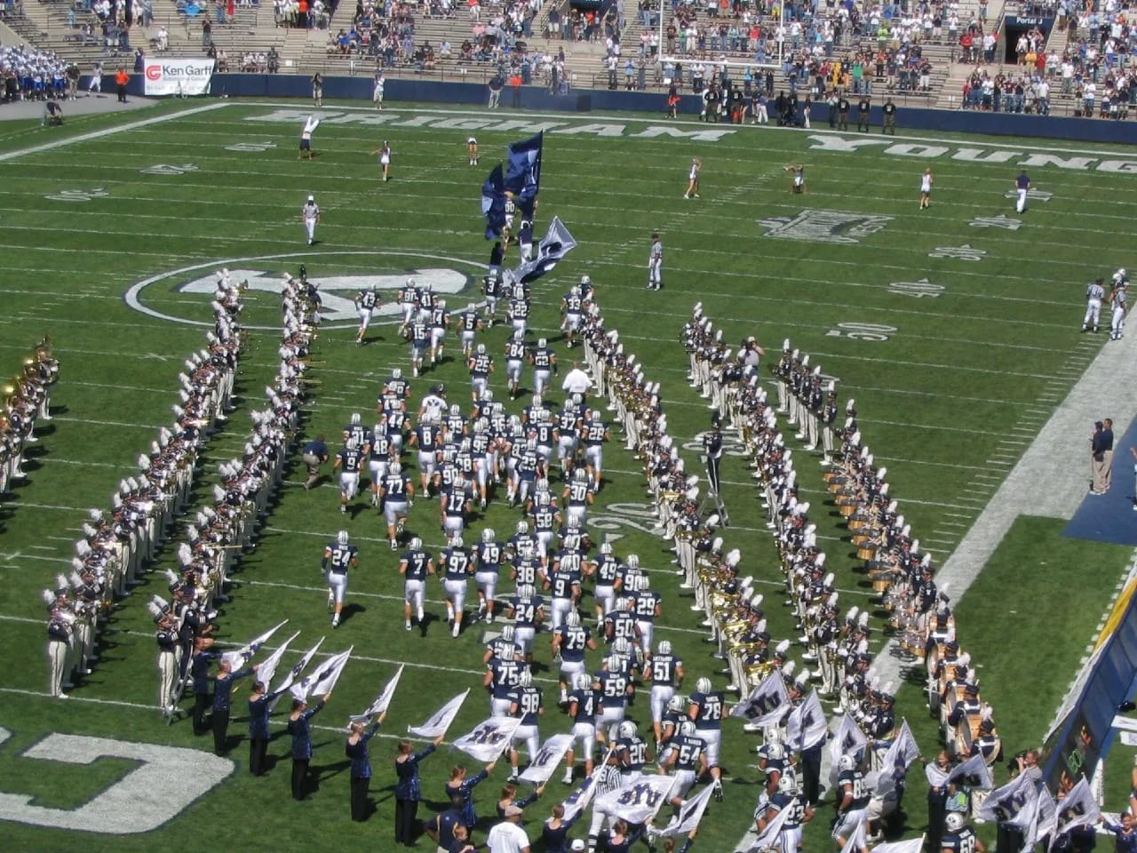 The BYU football team running onto the field at LaVell Edwards Stadium as the band forms up