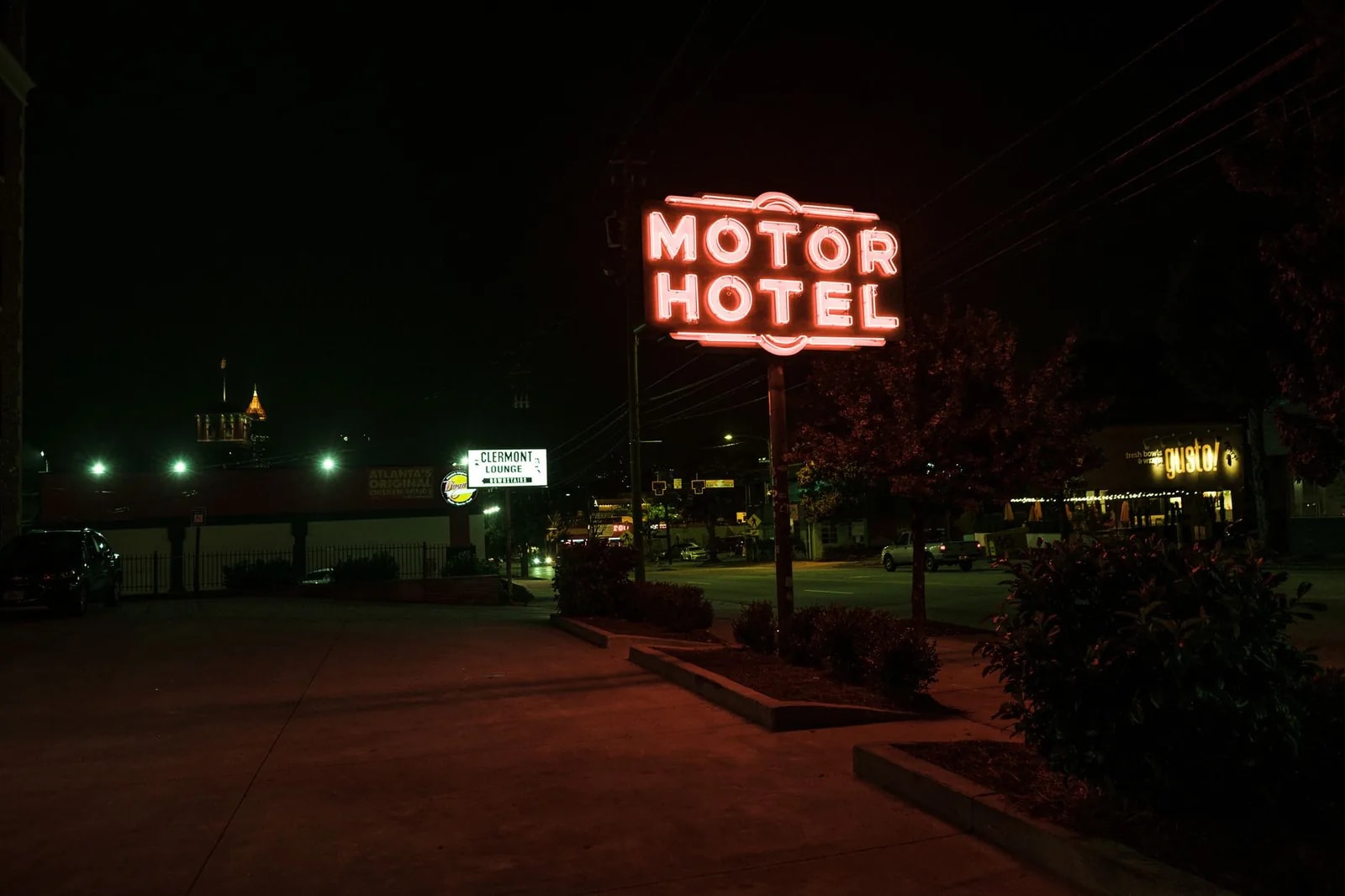 A red neon MOTOR HOTEL sign glowing above a low roadside building at night