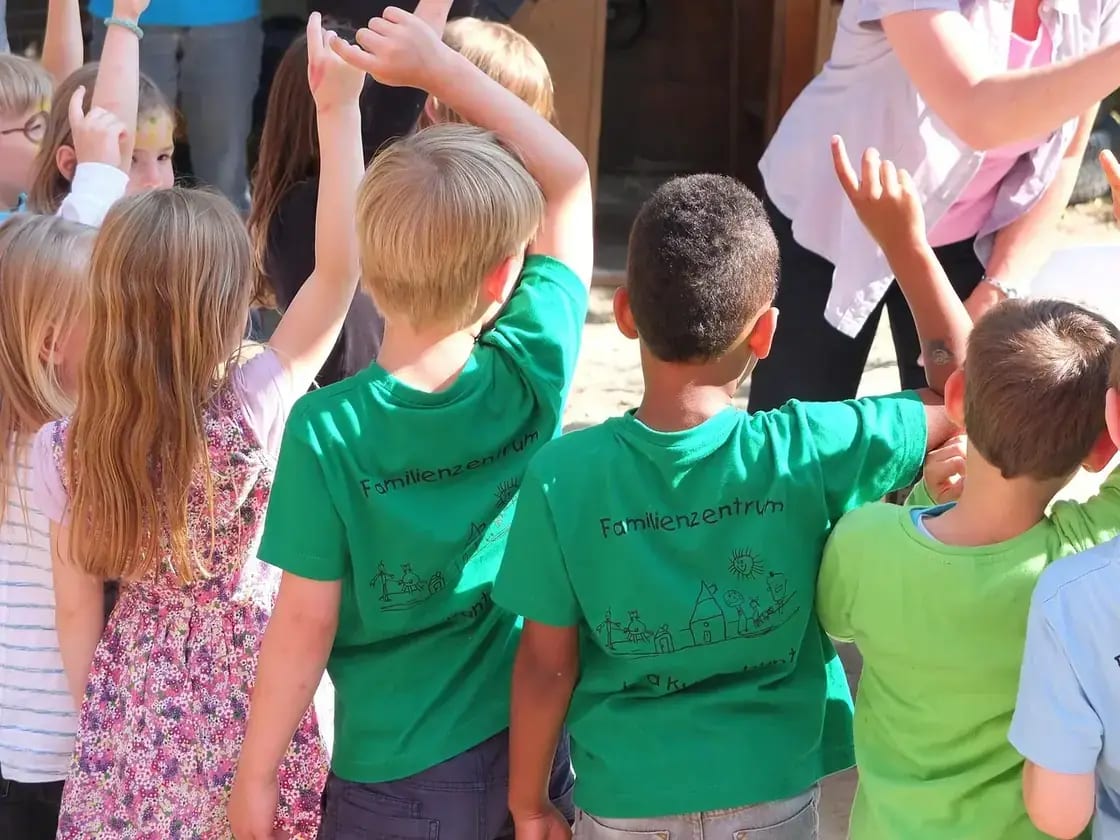 Young children raising their hands together at a daycare
