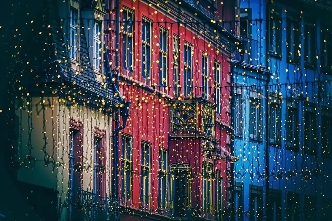 A brightly painted building strung with Christmas lights at night