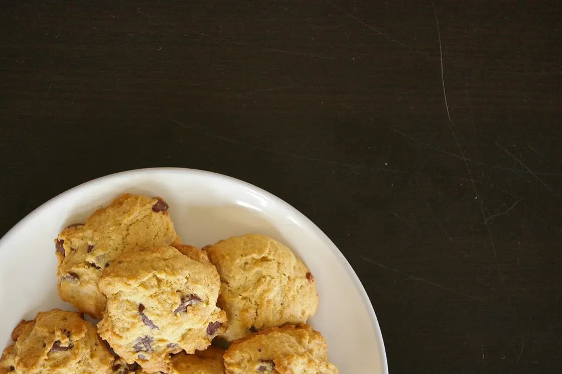 Chocolate chip cookies on a white plate against a dark background