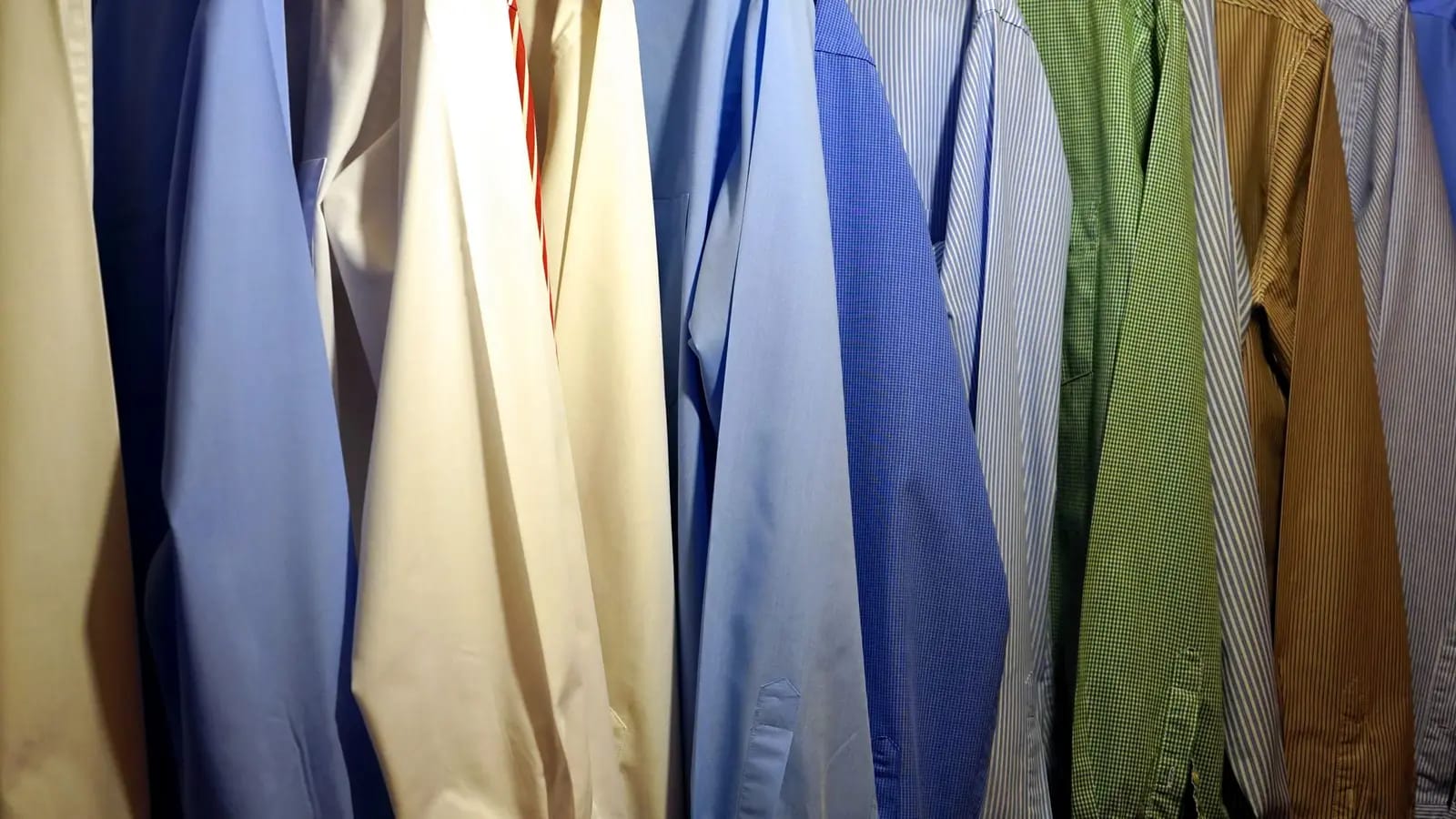 A packed rail of pressed shirts and jackets in blue, cream, green and striped fabrics