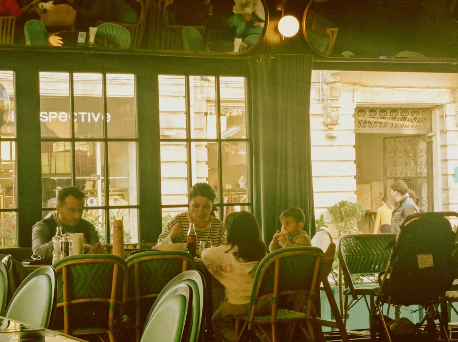Families eating together at a cafe seen from the sidewalk