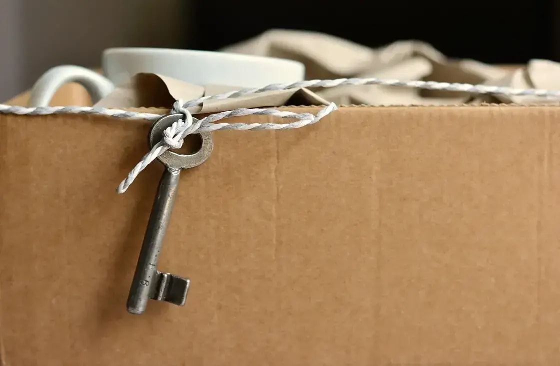 A key tied with string resting on a cardboard moving box