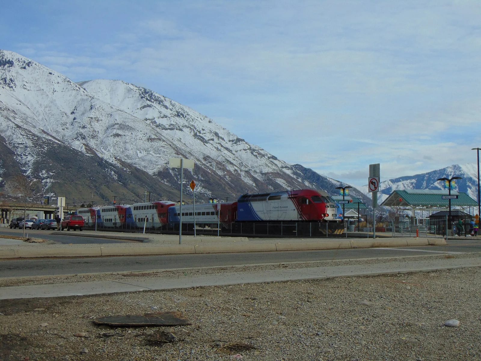 A FrontRunner train at the Provo station with a snow-covered mountain behind it
