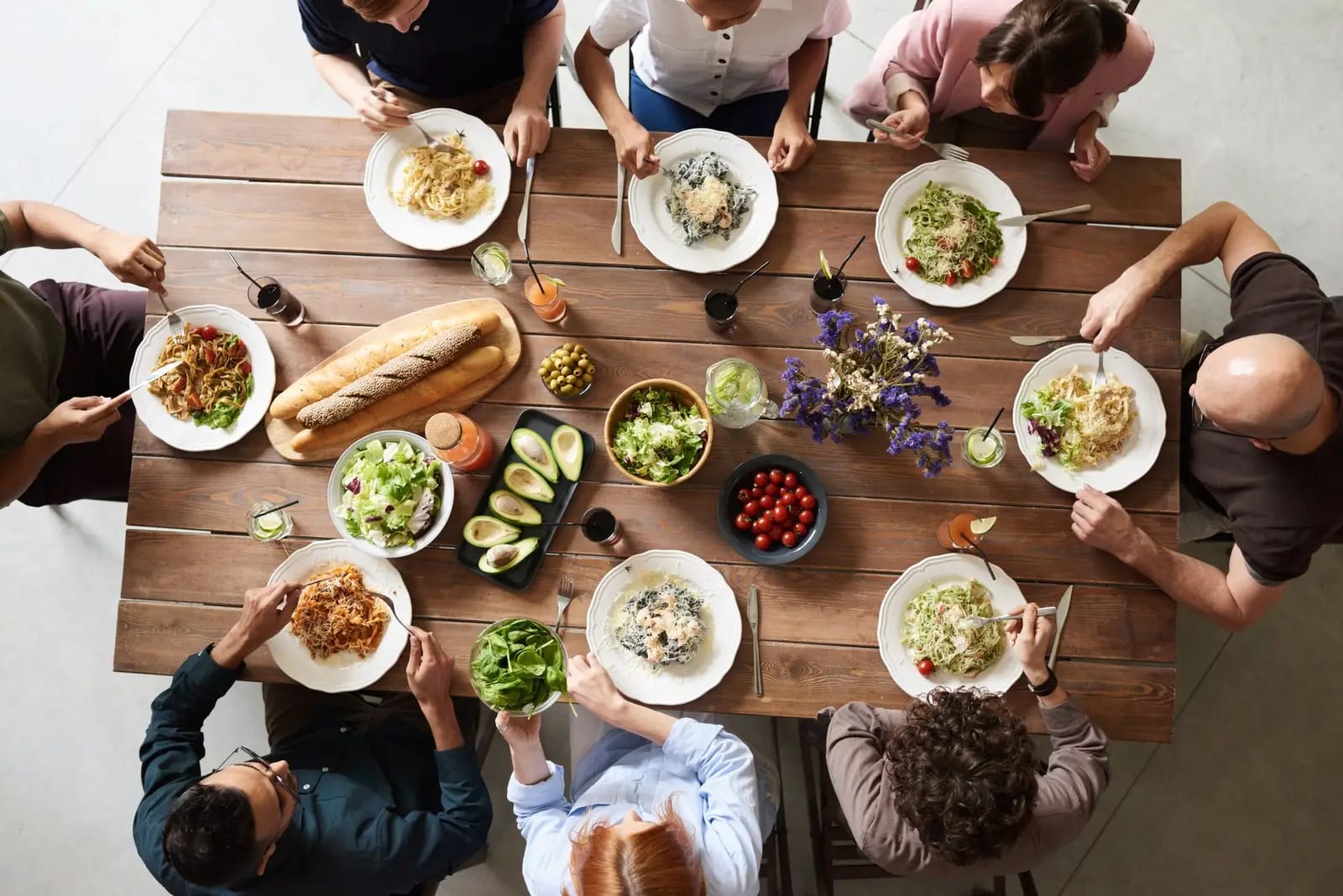 A diverse group of adults enjoying a shared meal indoors, viewed from above