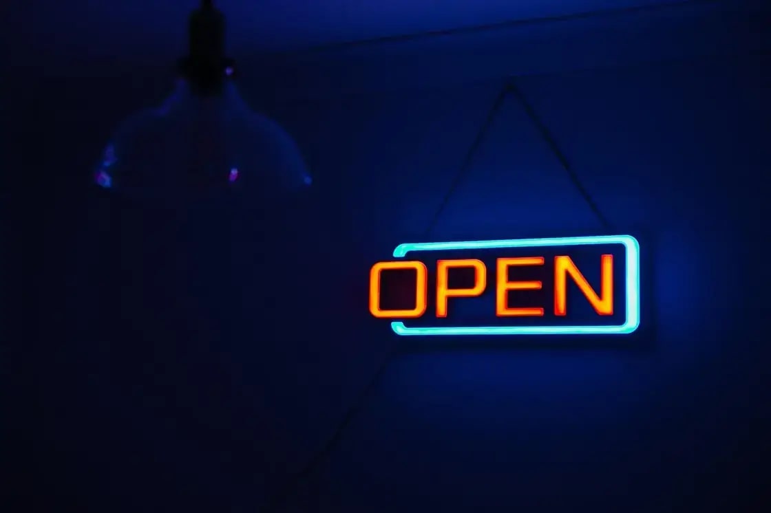 A neon OPEN sign glowing in a darkened window