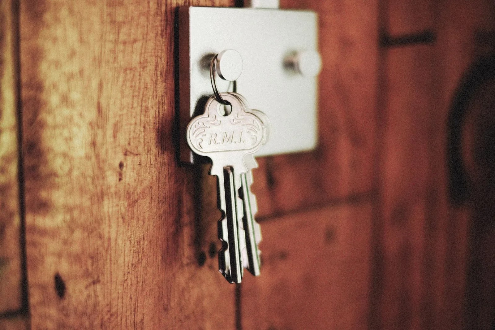 Keys hanging from the lock of a wooden door, with a decorative metal key fob