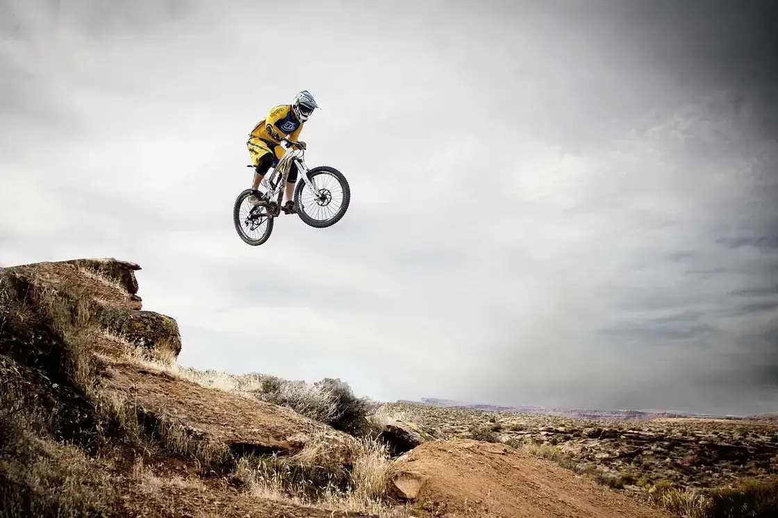 A mountain biker launching off a jump on a desert ridgeline