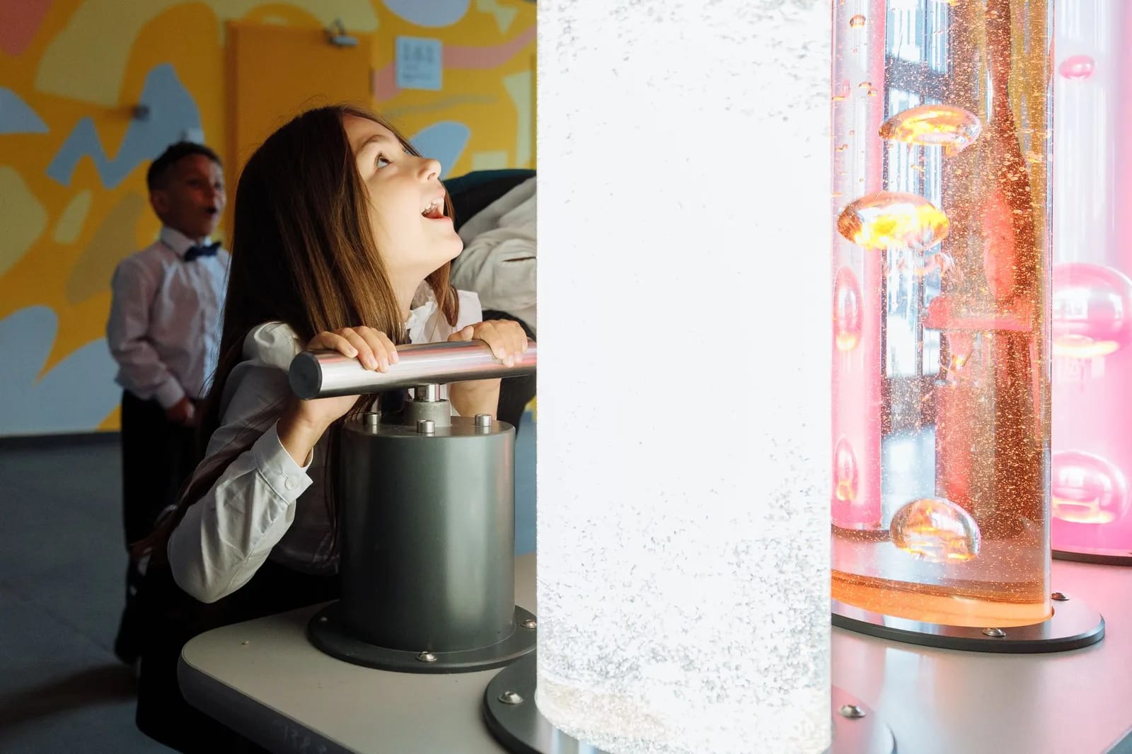 Children watching colored liquid rise in tubes at an interactive exhibit
