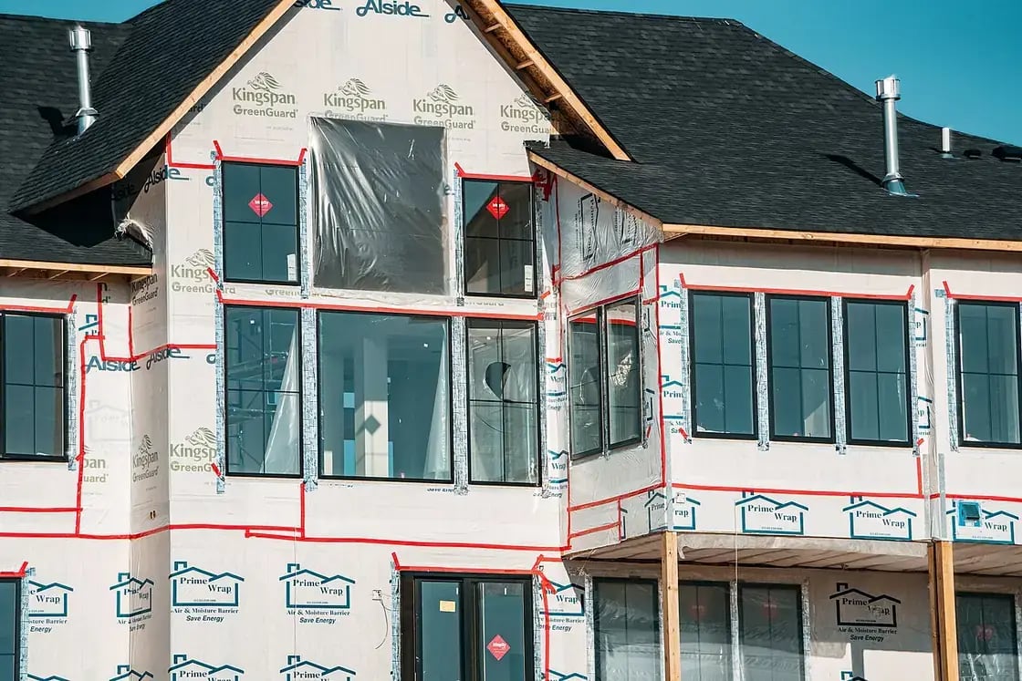 A new single-family home under construction, framed and partway through its build