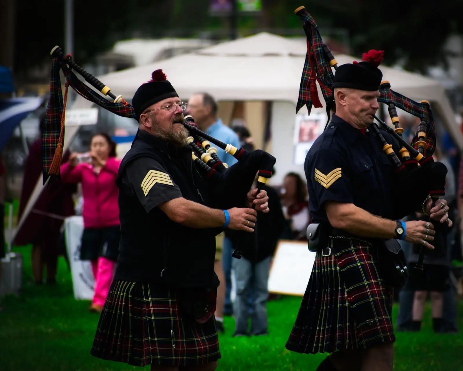 Scottish bagpipers in kilts performing at an outdoor festival