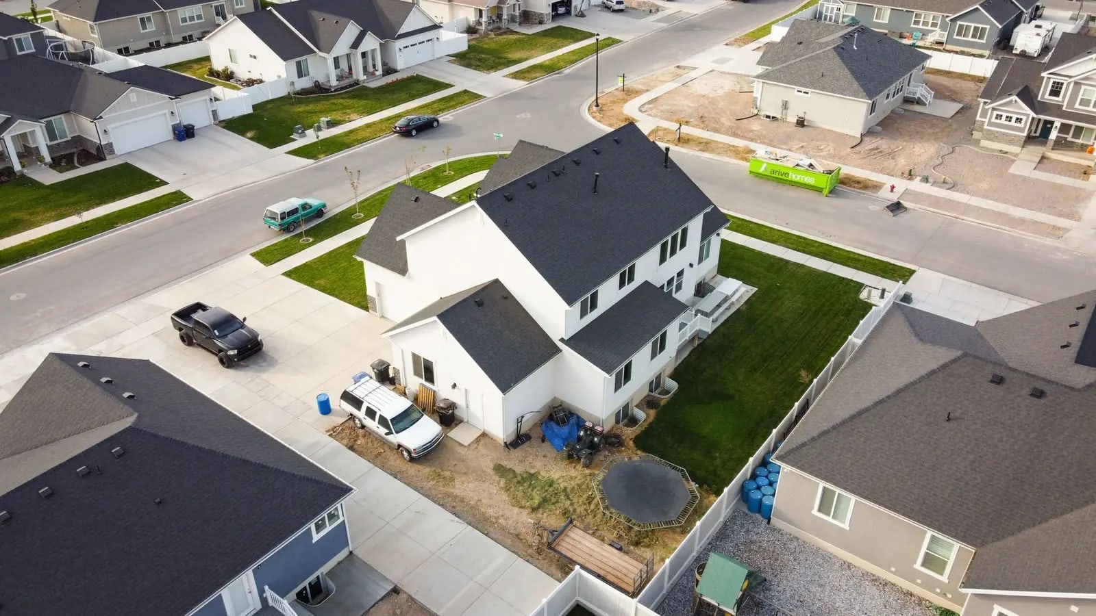 An aerial view of a suburban neighborhood of detached houses with driveways and wide streets