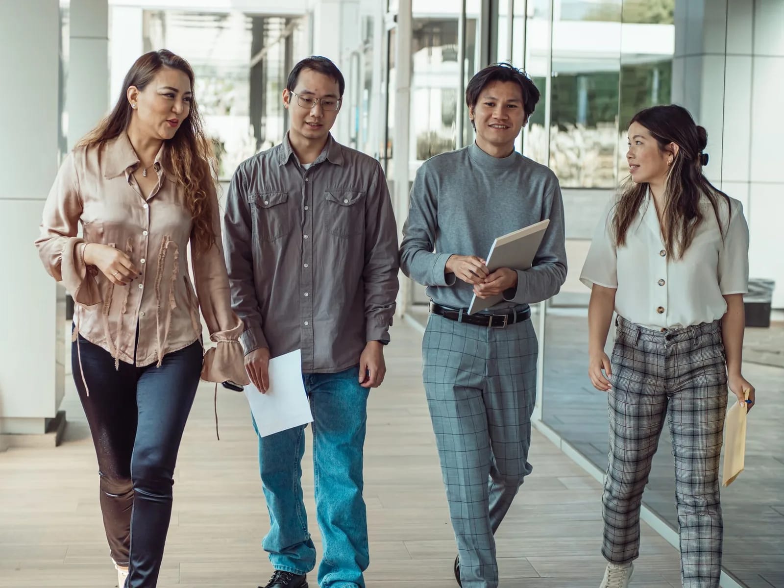 A group of young adults standing and talking outside a brick building