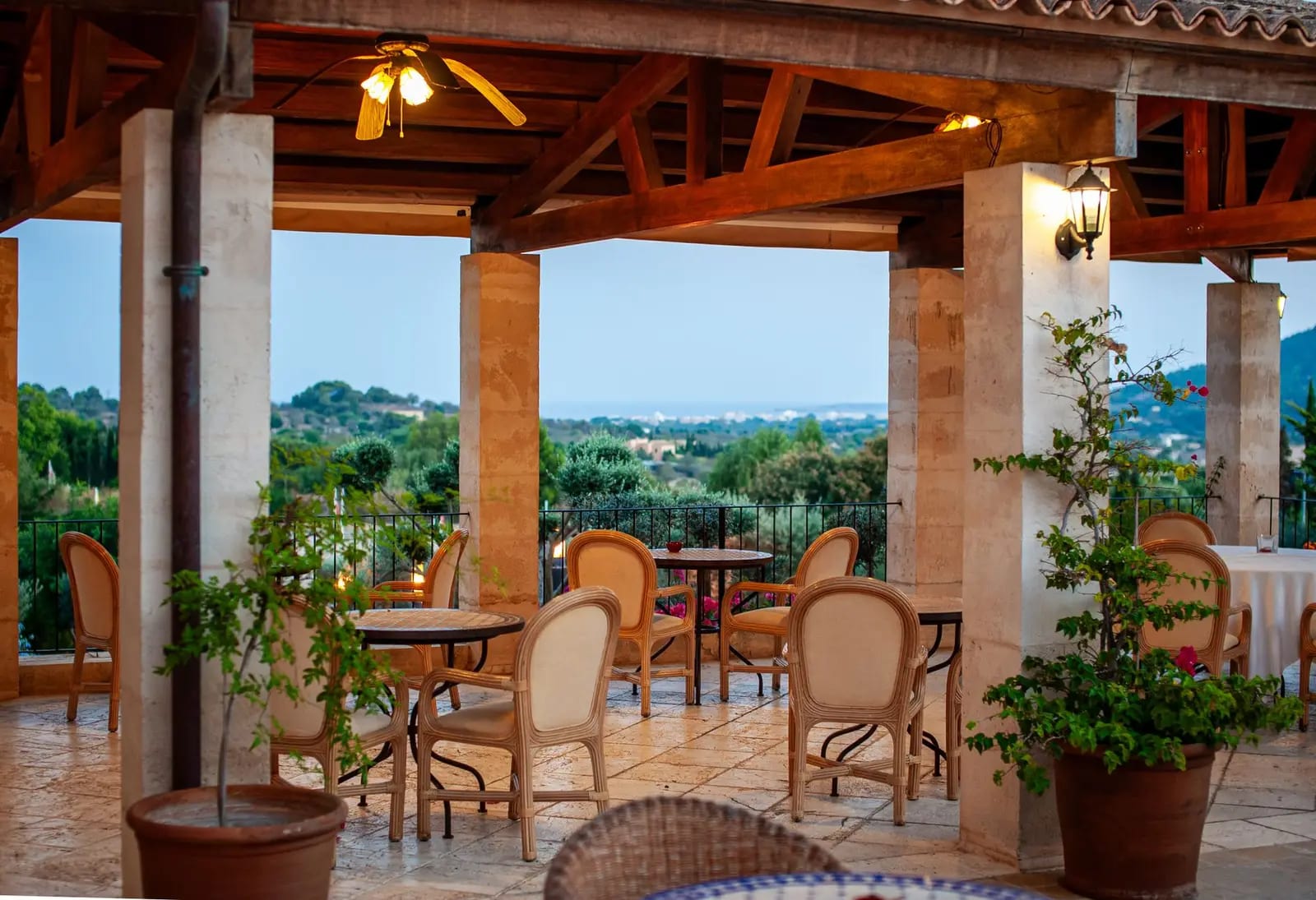 An empty restaurant terrace set for dinner, open to the view beyond