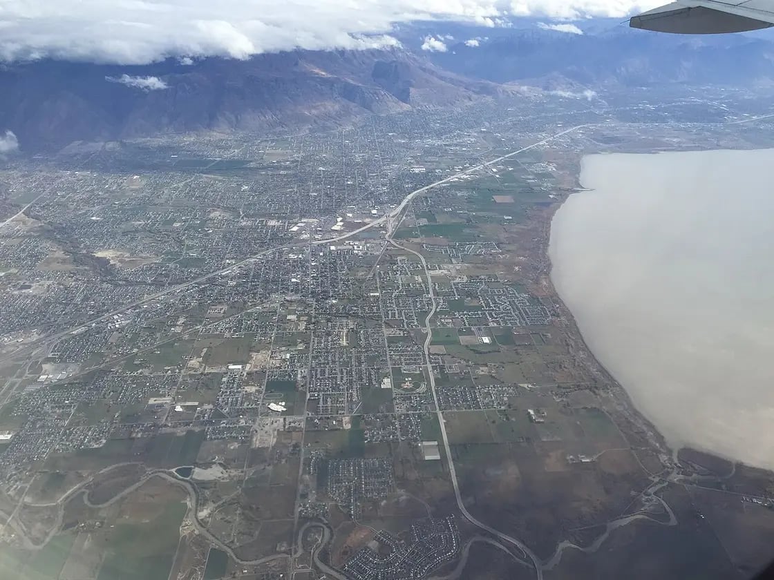 An aerial view of a valley city stretching to the shore of a large lake