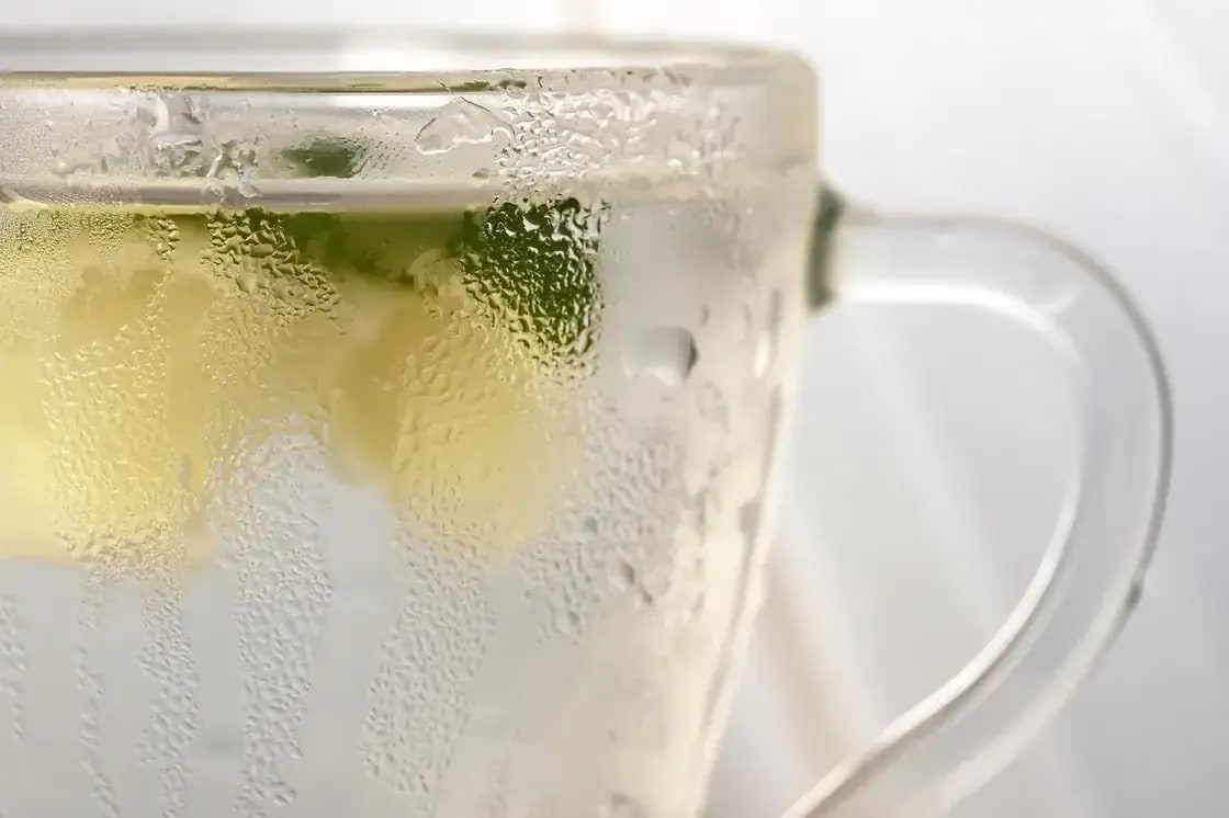 A frosted glass mug of iced soda with a wedge of lime
