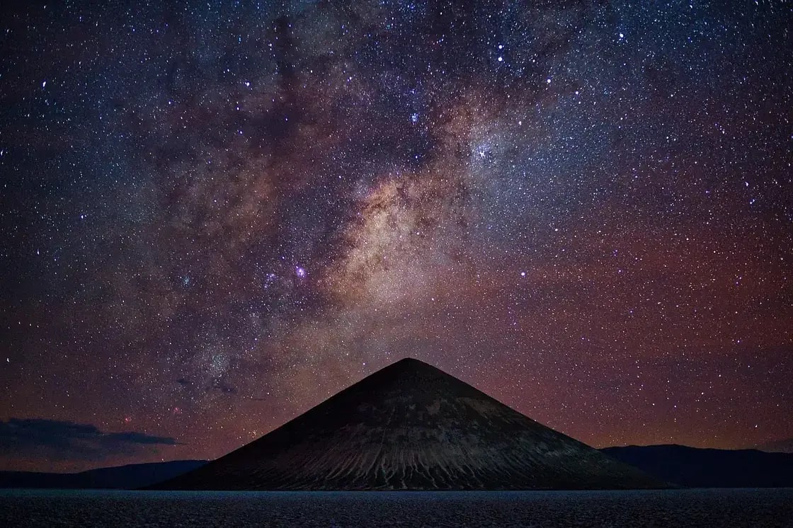 The Milky Way arching over a dark mountain silhouette