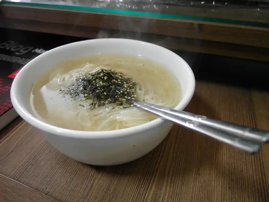 A steaming bowl of instant noodles on a wooden table