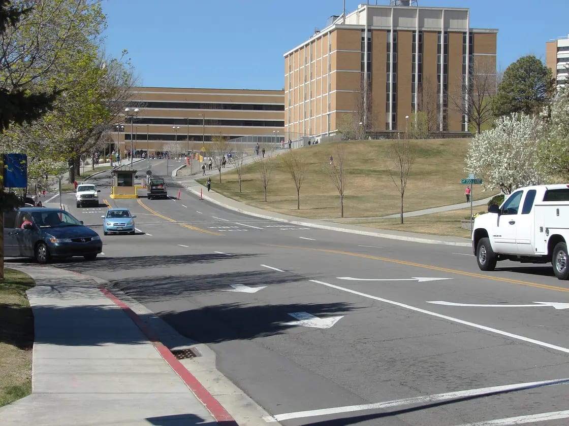 A residential street intersection near BYU in Provo, Utah, with cars parked along the curb