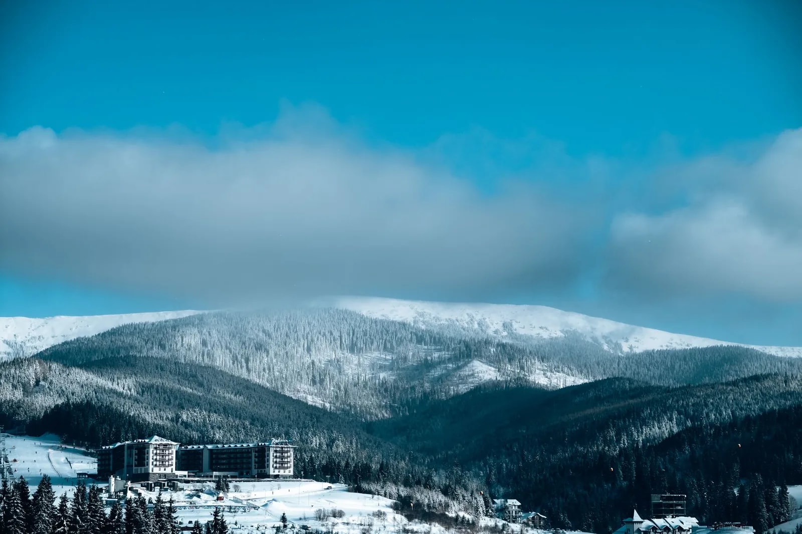 A mountain resort at the foot of a snow-covered forested slope