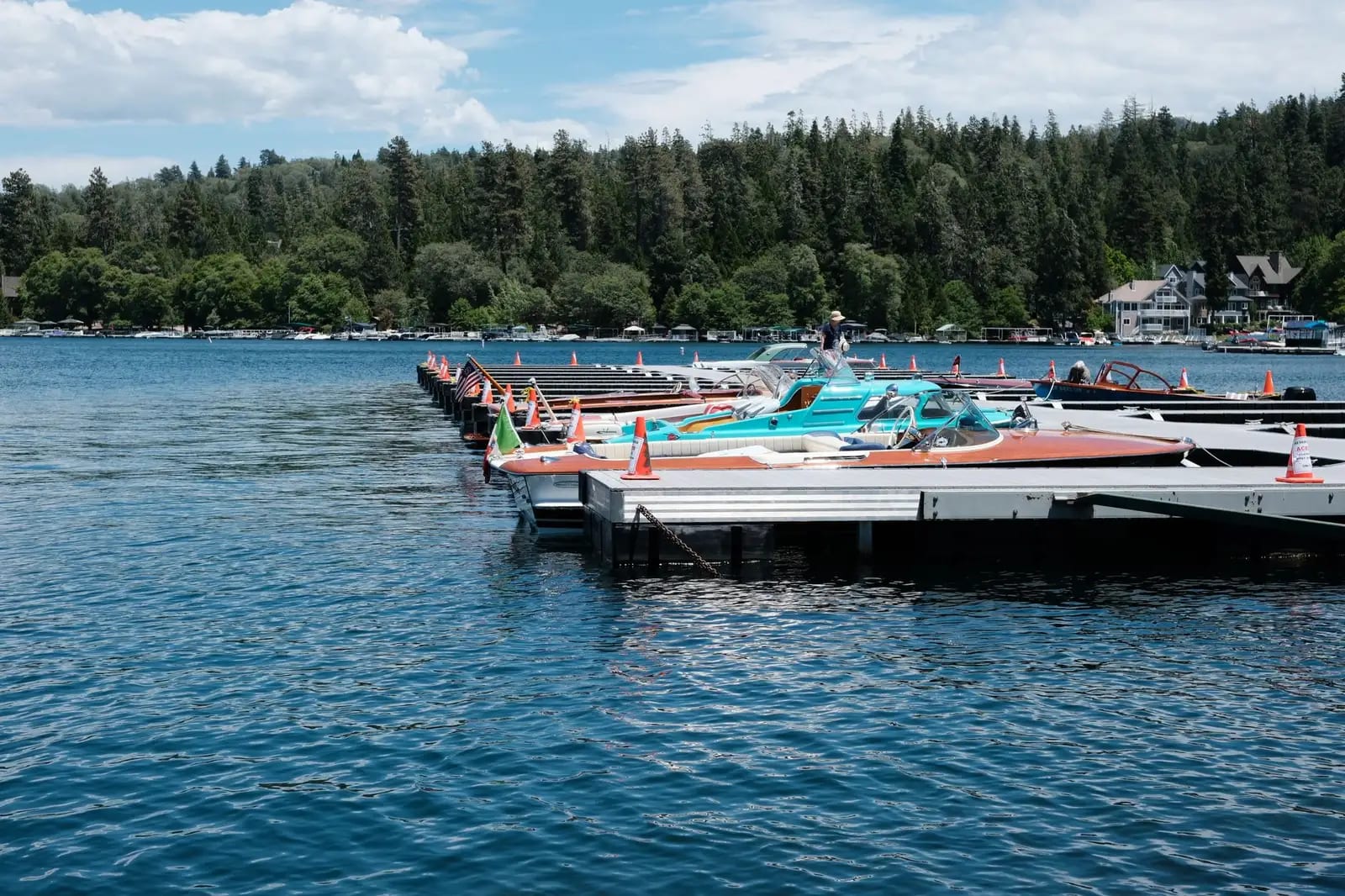 Peaceful view of boats docked at a lakeside surrounded by lush forest under a clear sky