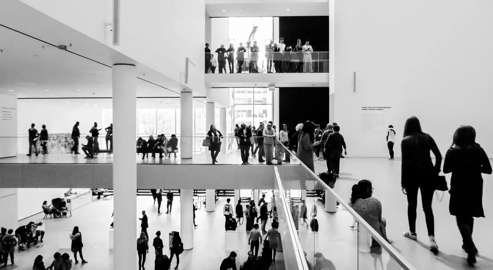A dynamic black and white image of people in a modern museum setting